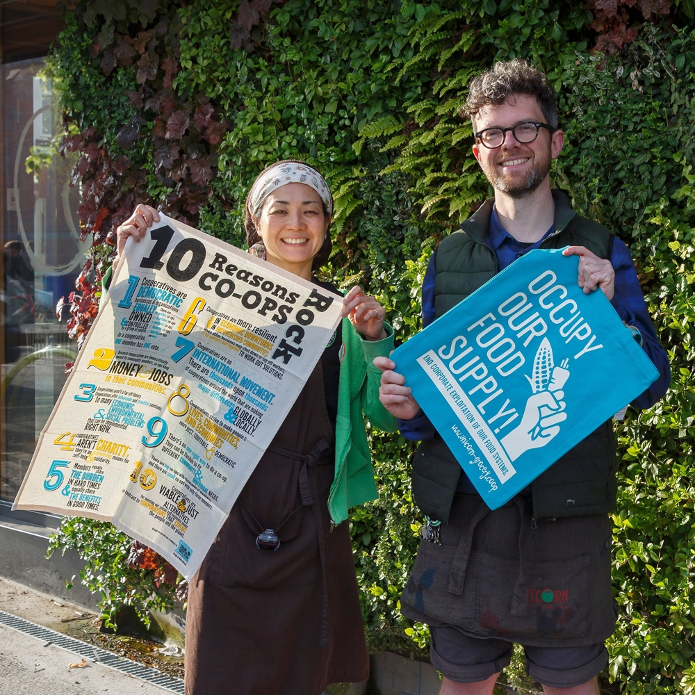 A couple hold branded tea towels that champion co-operative working