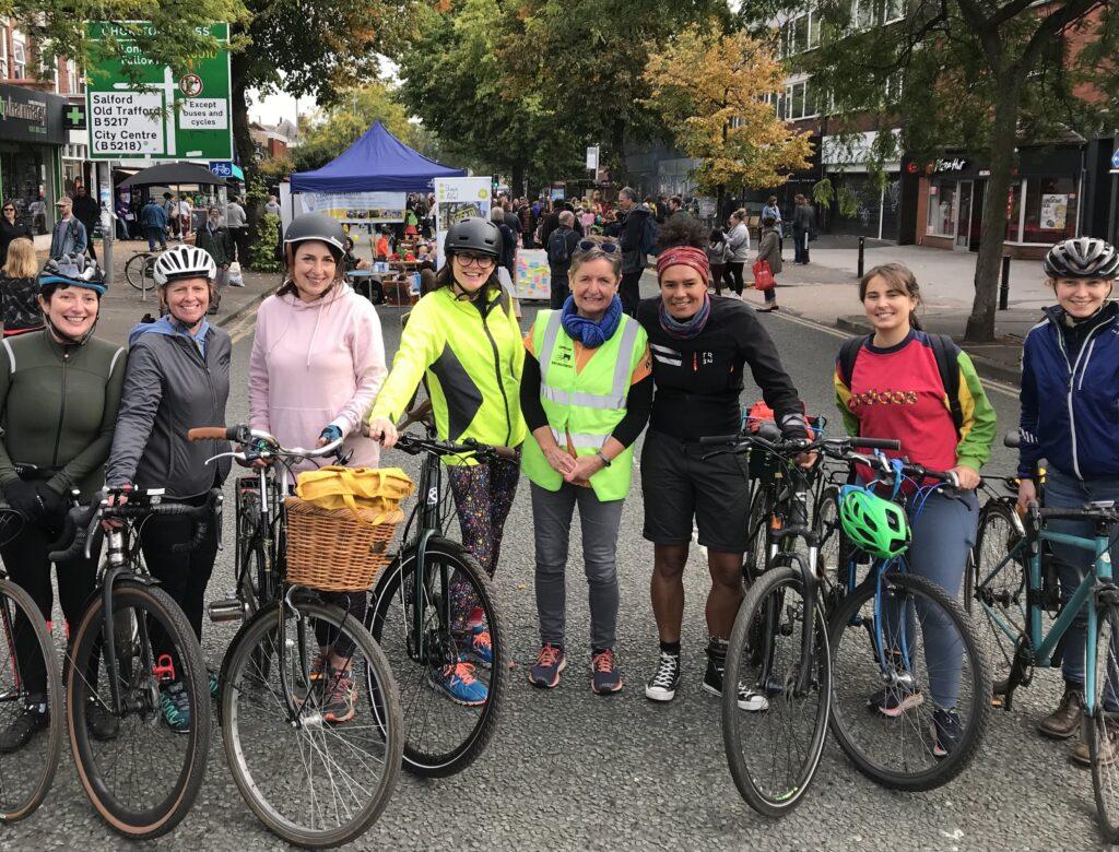 A row of happy cyclists, standing by their bikes.